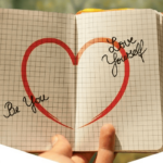 Carnet ouvert avec un cœur dessiné au centre et les mots 'Be You' et 'Love Yourself'