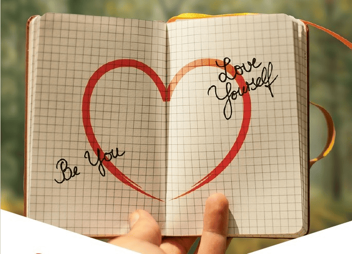 Carnet ouvert avec un cœur dessiné au centre et les mots 'Be You' et 'Love Yourself'